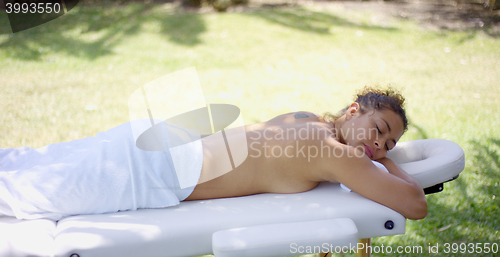 Image of Sleeping woman in towel laying on massage table