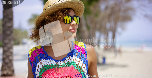 Image of Grinning woman in sunglasses and hat near ocean
