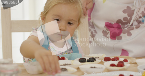 Image of Child and woman preparing muffins on table