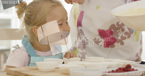 Image of Happy little girl with empty muffin holders