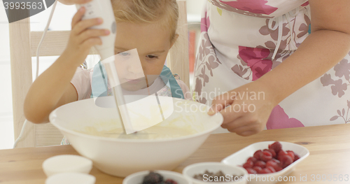 Image of Serious pretty little girl concentrating on baking