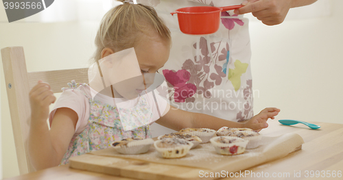 Image of Child interested in sugar falling on baked muffins