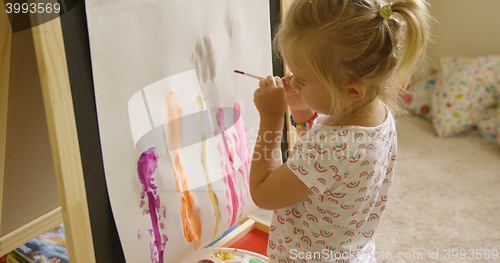 Image of Little girl standing painting at an easel