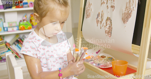 Image of Cute little girl choosing a paint brush