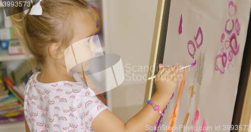 Image of Creative little girl painting in a playroom