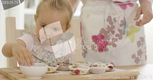 Image of Close up on girl helping to prepare muffins