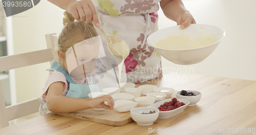 Image of Parent pouring muffin batter into holders