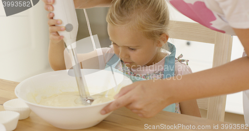 Image of Cute little girl learning to bake from mother