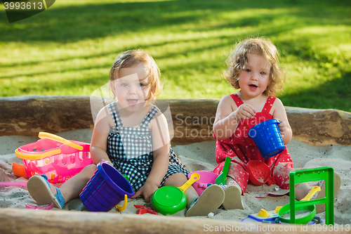 Image of The two little baby girls playing toys in sand