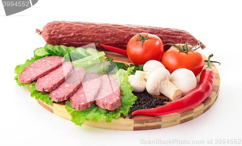 Image of sliced sausage with vegetables on board