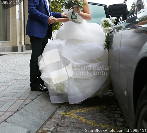 Image of Beautiful couple, bride and groom getting into wedding limousine