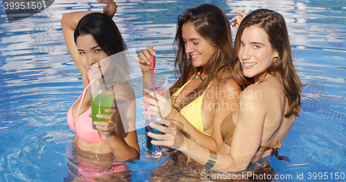 Image of Three gorgeous women in pool with colorful drinks