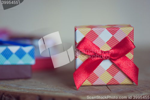 Image of Gift box with red bow on wood background