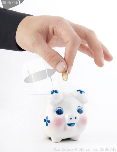 Image of Hand inserting coin into piggy-bank