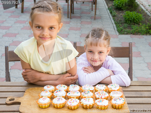 Image of Two sisters sitting at a table on which are freshly baked Easter cupcakes
