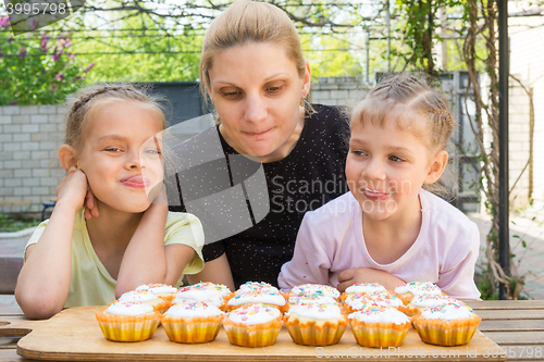 Image of Mother and two daughters salivate looking at freshly Easter cupcakes