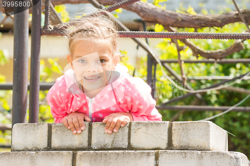 Image of Seven Years\' happy girl hanging on a brick fence and looked in the frame