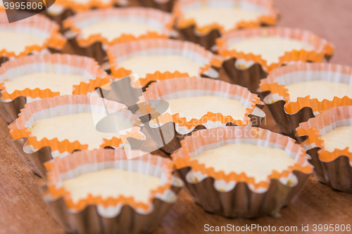 Image of Three rows of molds with the dough for making cakes