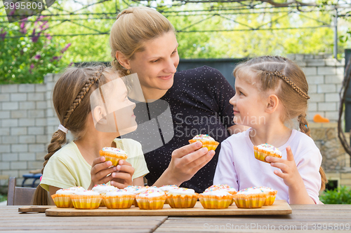 Image of Mother and two daughters sitting at the table with Easter cupcakes in his hands