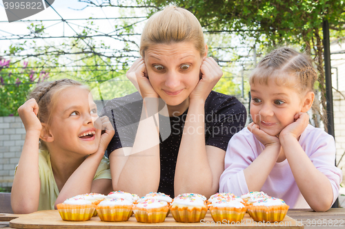 Image of Mother and two daughters having fun and looking at easter cupcakes