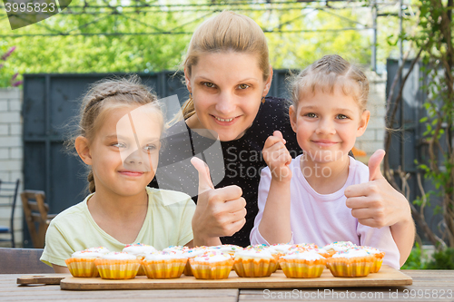 Image of Mother and two daughters show a thumbs-up, and dress easter cupcakes