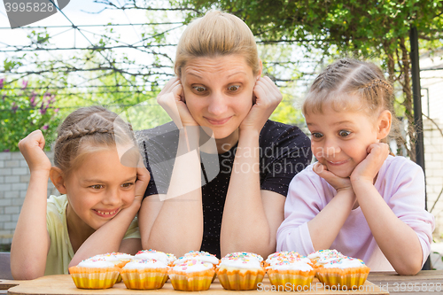 Image of Mother and two daughters with a good appetite and big eyes looking at easter cupcakes