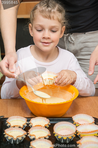 Image of Daughter holds the mold for the cake, while my mother draws the dough from the bowl