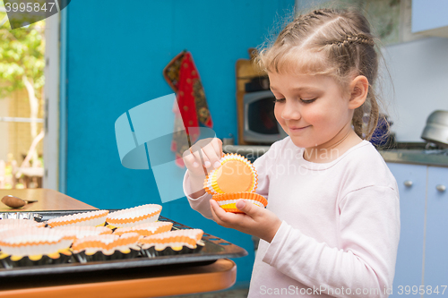 Image of The child is prepared for the feast of Easter, laying on a baking tins Easter cupcakes