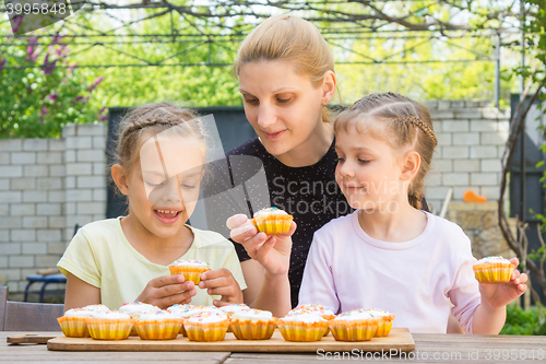 Image of Mother and two daughters sitting at the table with Easter cupcakes and they are risen