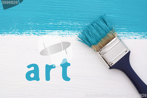 Image of Stripe of turquoise paint, paintbrush and the word ART