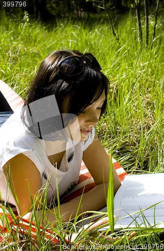 Image of pretty young brunette readind in the park