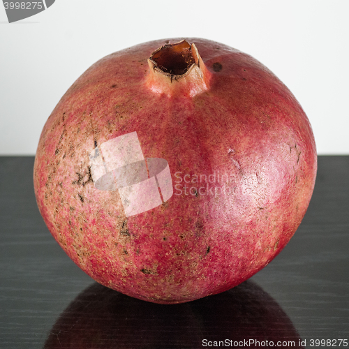 Image of  half ripe pomegranate fruit isolated on black wooden plane and white background 