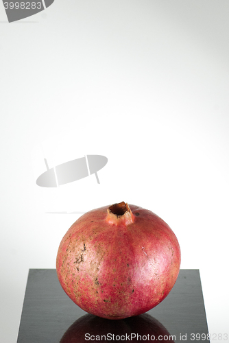 Image of  half ripe pomegranate fruit isolated on black wooden plane and white background with copyspace