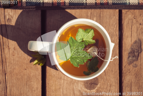 Image of Top view of tea with currant leaf in white cup. Horizintal image