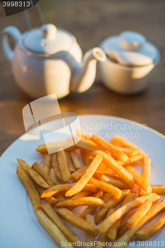 Image of French fries with ketchup and on wooden table. Top view sunny evening