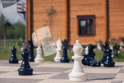 Image of big chess on a background of  wooden house and grass field