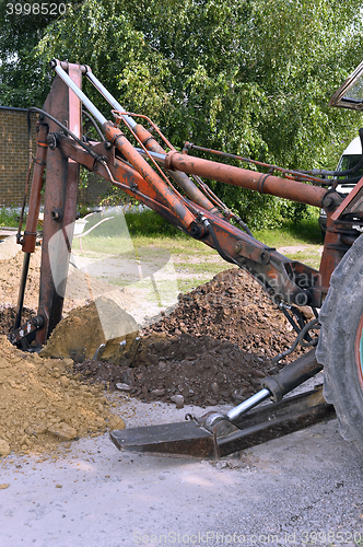 Image of Excavator bucket digging a trench in the dirt ground