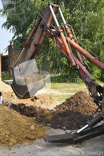 Image of Excavator bucket digging a trench in the dirt ground