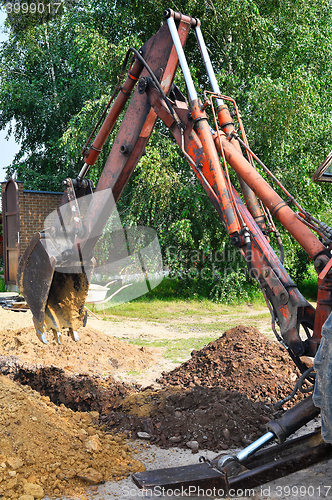 Image of Excavator bucket digging a trench in the dirt ground