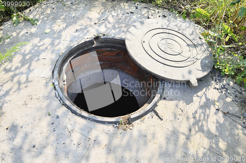 Image of Concrete cesspit with an open hatch on the ground in the summer