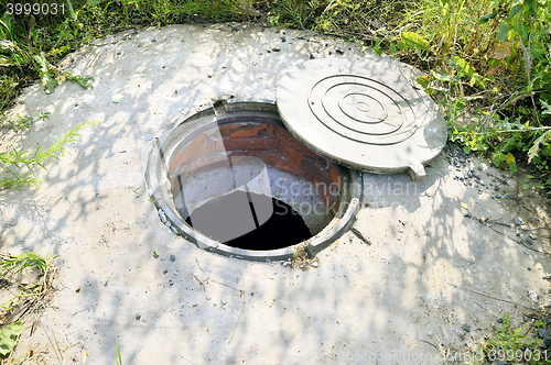 Image of Concrete cesspit with an open hatch on the ground in the summer