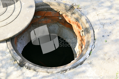 Image of Concrete cesspit with an open hatch on the ground in the summer