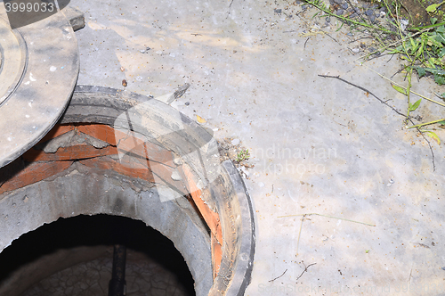 Image of Concrete cesspit with an open hatch on the ground in the summer