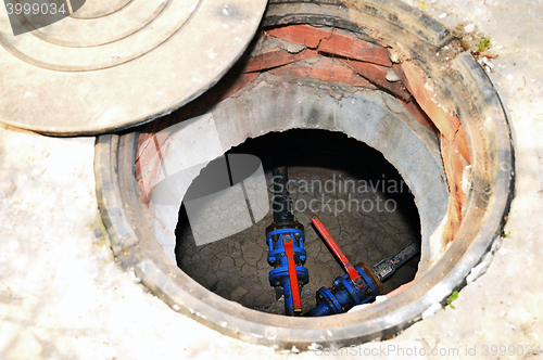 Image of Concrete cesspit with an open hatch on the ground in the summer