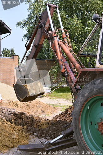 Image of Excavator bucket digging a trench in the dirt ground