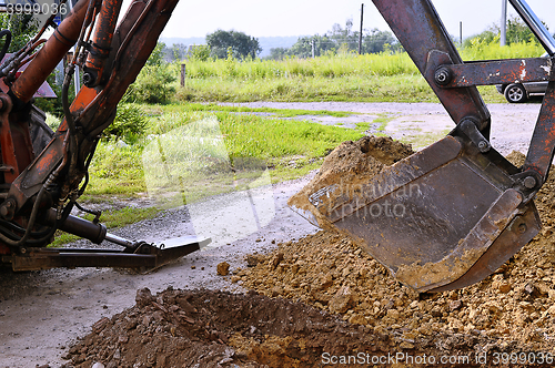 Image of Excavator bucket digging a trench in the dirt ground