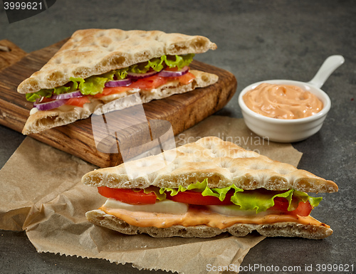 Image of various sandwiches on paper and wooden cutting board