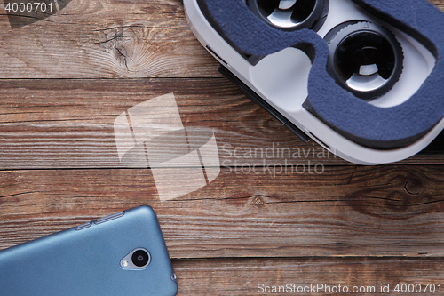 Image of Modern smartphone with empty screen and virtual reality goggles