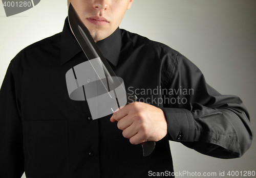 Image of standing man in black with knife