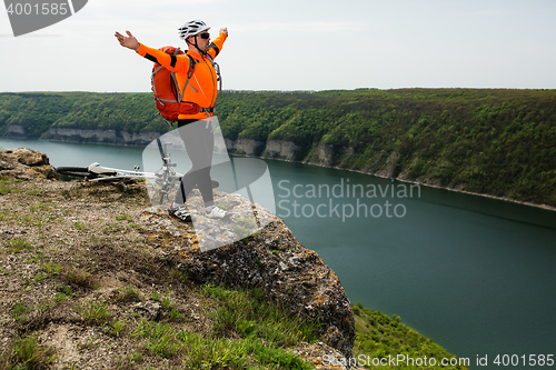 Image of Cyclist in Orange Wear Riding the Bike above River